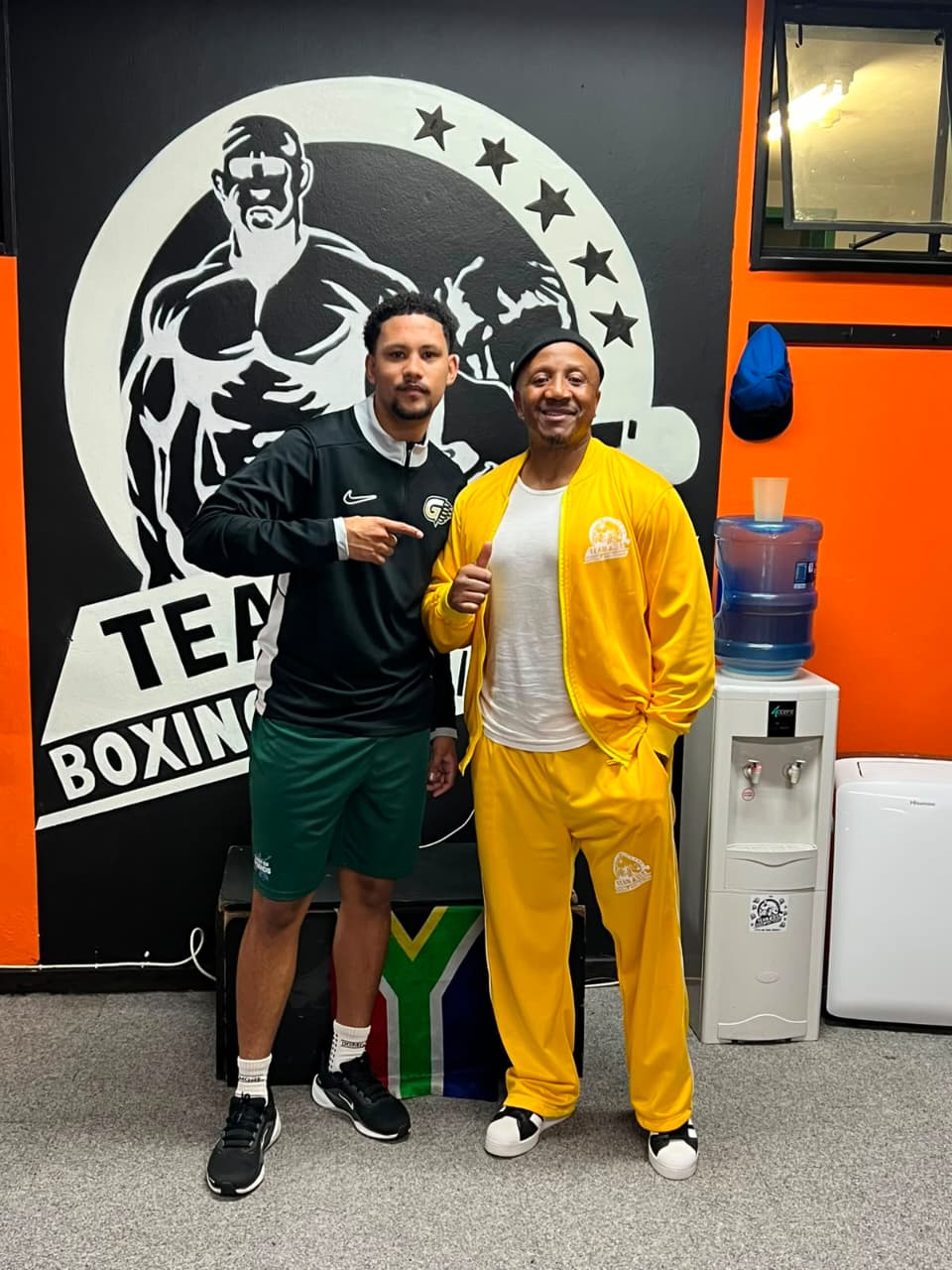 Team Dida gym members in front of the gym mural