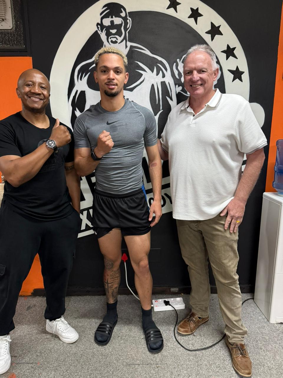 Team Dida gym members in front of the gym mural